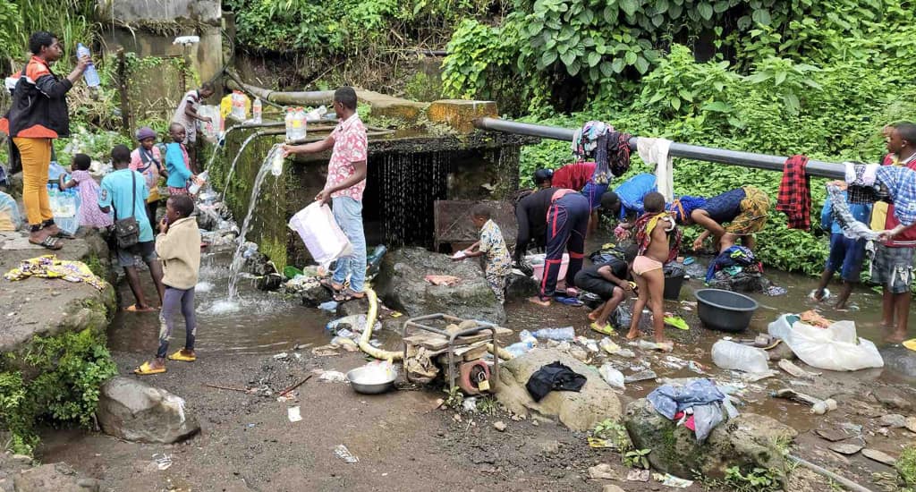 Community members collecting water and washing at a spring catchment