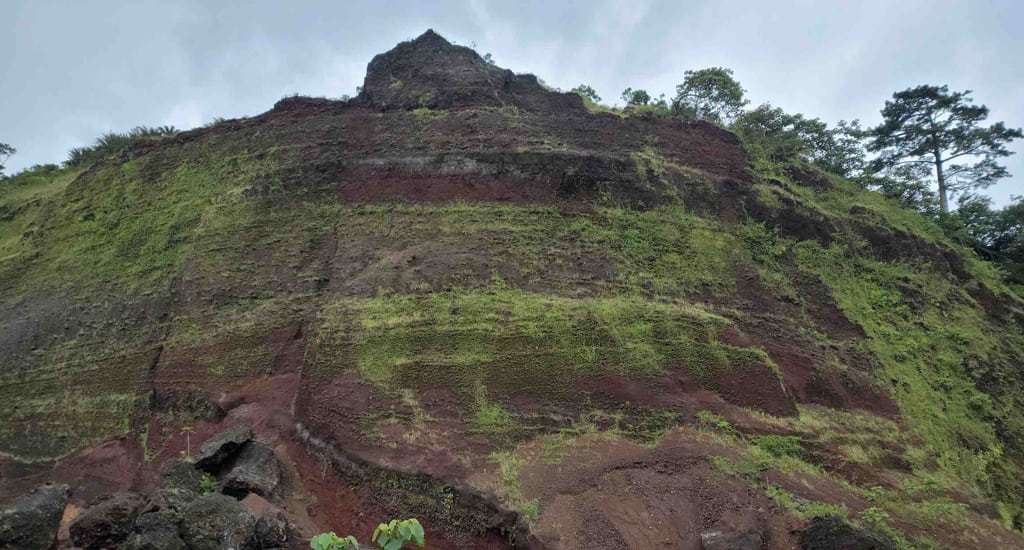 Eroded red-soil slope above a quarry site